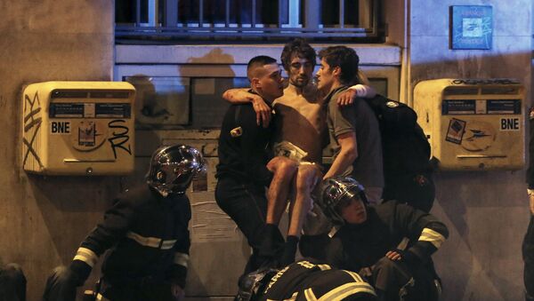 Miembros de la brigada de bomberos ayudan a una persona lesionada, cerca del teatro Bataclán, París - Sputnik Mundo