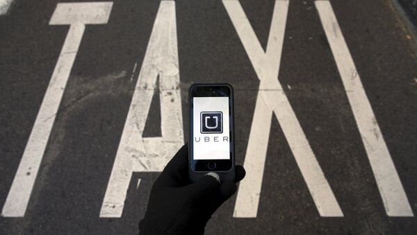 The logo of car-sharing service app Uber on a smartphone over a reserved lane for taxis in a street is seen in this file photo illustration taken in Madrid on December 10, 2014 - Sputnik Mundo