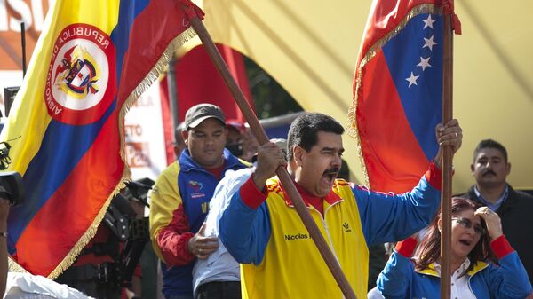 Venezuela's President Nicolas Maduro holds up a Colombian national flag, left, alongside his country's national flag, during a rally in support of closing the Colombian border, in Caracas, Venezuela, Friday, Aug. 28, 2015. - Sputnik Mundo