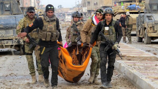 Miembros de las fuerzas de seguridad iraquíes llevan el cuerpo de un militar en Ramadi - Sputnik Mundo