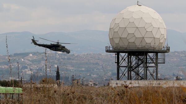 Un helicóptero vuela cerca de un radar en la base militar rusa Hmeymim en Siria - Sputnik Mundo