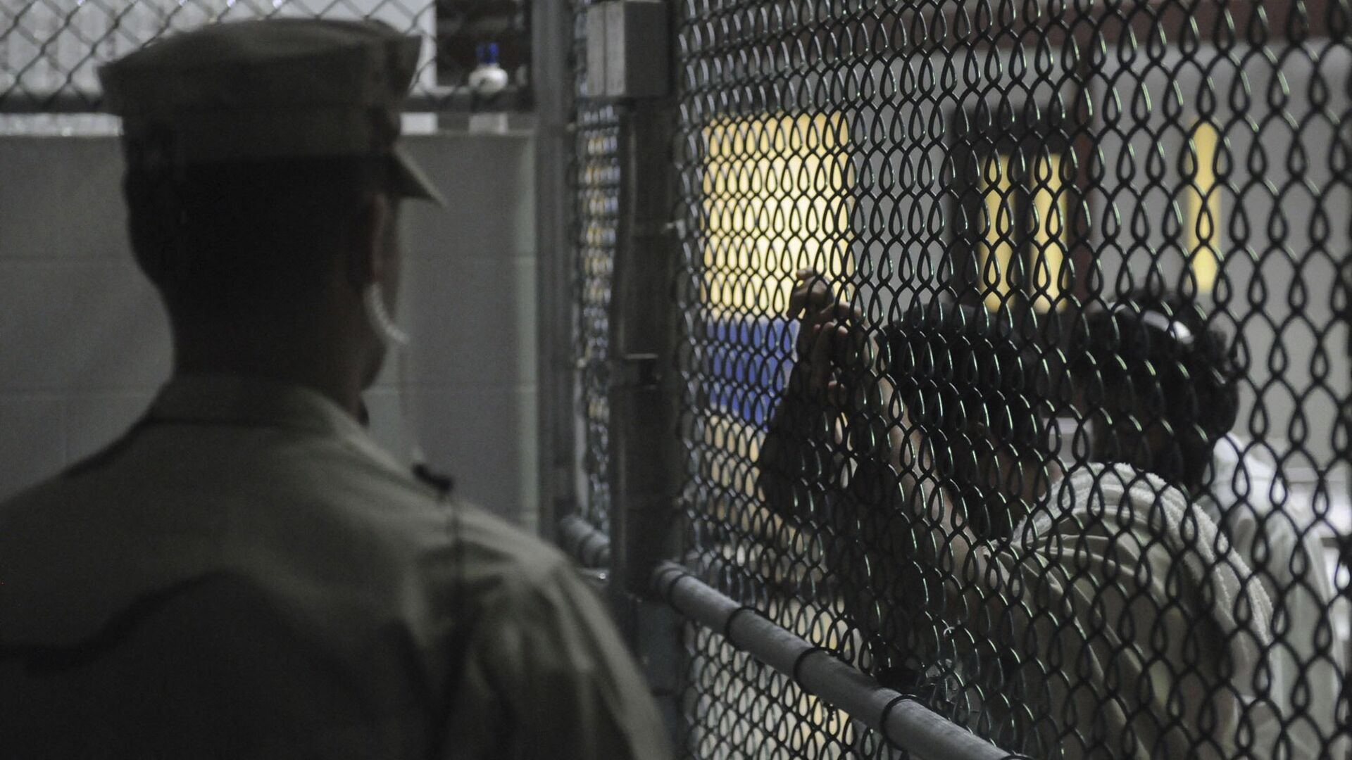 A Sailor assigned to the Navy Expeditionary Guard Battalion stands watch over detainees in a cell block in Camp 6 at Guantanamo Bay naval base in a March 30, 2010 file photo provided by the US Navy. - Sputnik Mundo, 1920, 12.01.2022