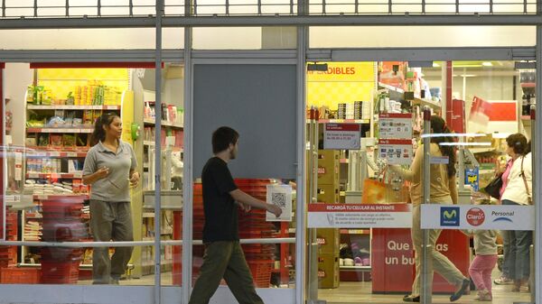 People walk past a supermarket with a promotional poster on its window in Buenos Aires on February 19, 2013. Argentines fear inflation may reach a rate of 30% this year, after a new price freeze has gone into effect until April 1. - Sputnik Mundo