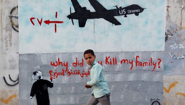A Yemeni boy (C) walks past a mural depicting a US drone and reading  Why did you kill my family on December 13, 2013 in the capital Sanaa. - Sputnik Mundo