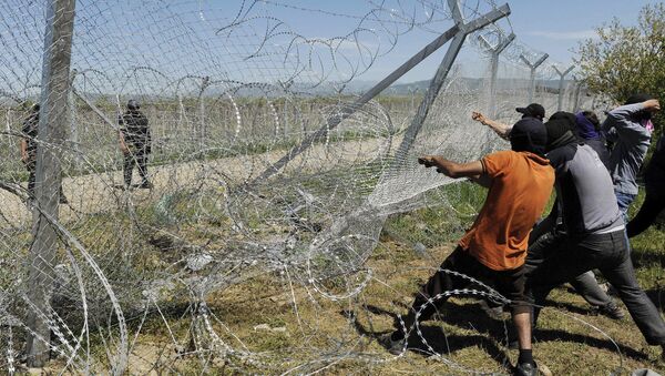 Migrantes intentan derrumbar una parte de la valla fronteriza entre Grecia y Macedonia (archivo) - Sputnik Mundo