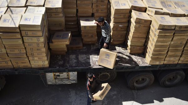 Hombres sirios descargan paquetes de ayuda proporcionados por el Programa Mundial de Alimentos (PMA) de la ONU y la Media Luna Roja Árabe Siria - Sputnik Mundo