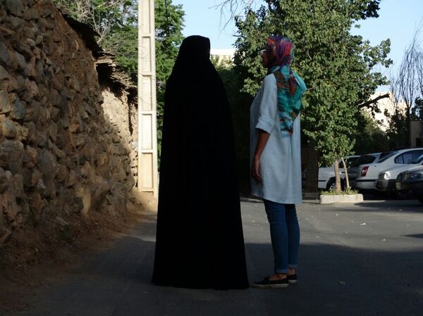 Actualmente, en la capital y en otras ciudades iraníes, la mayoría de las mujeres llevan puestos dos tipos de hiyab: el chador —izquierda—, que cubre todo el cuerpo salvo el rostro, y el velo colorido —derecha—, que cubre únicamente la cabeza. La primera opción es más conservadora; la segunda, más moderna, es muy popular entre las jóvenes. Actualmente, en la capital y en otras ciudades iraníes, la mayoría de las mujeres llevan puestos dos tipos de hiyab: el chador —izquierda—, que cubre todo el cuerpo salvo el rostro, y el velo colorido —derecha—, que cubre únicamente la cabeza. La primera opción es más conservadora; la segunda, más moderna, es muy popular entre las jóvenes. - Sputnik Mundo