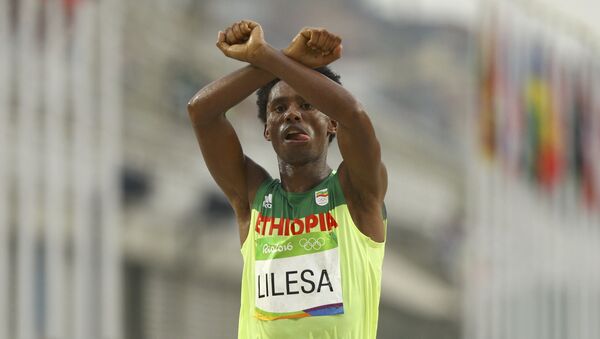 Lilesa cruzando la meta y haciendo un gesto como si tuviera los brazos esposados, en señal de protesta contra la persecución del Gobierno etíope contra la etnia oromo - Sputnik Mundo