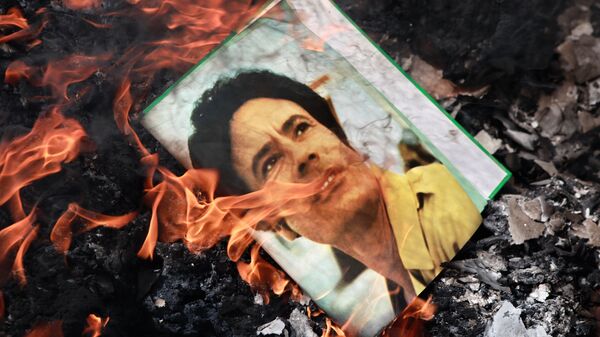 El retrato de Muamar Gadafi, quemado en la calle de Benghazi, Libia, en 2011 - Sputnik Mundo
