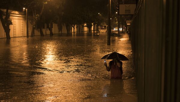 A man wades through a flooded street at the Jardim Botanico neighborhood after heavy rains in Rio de Janeiro, Brazil, Saturday, March 12, 2016 - Sputnik Mundo