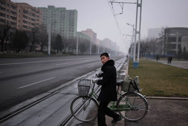 Un joven empuja una bicicleta en una calle de la capital norcoreana Un joven empuja una bicicleta en una calle de la capital norcoreana - Sputnik Mundo
