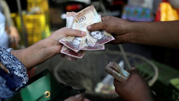 A cashier receives Venezuelan bolivar notes from a customer at a street market in downtown Caracas, Venezuela - Sputnik Mundo