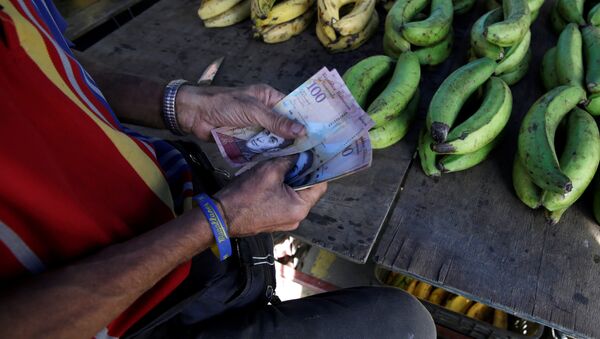 A vendor counts Venezuelan bolivar notes at his stall in a street market in the slum of Petare in Caracas, Venezuela - Sputnik Mundo