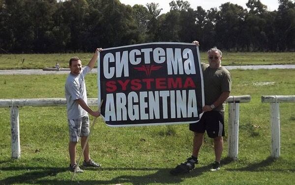 Personas sostienen un cartel de Systema Argentina - Sputnik Mundo