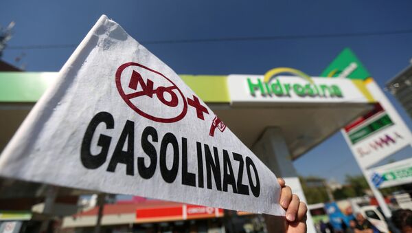 Un hombre sostiene un letrero durante una manifestación contra el aumento de los precios de la gasolina en Ciudad de México - Sputnik Mundo
