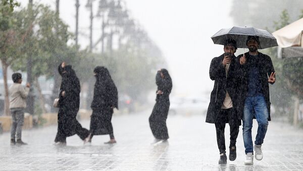 La gente bajo la lluvia en una calle de Riad - Sputnik Mundo