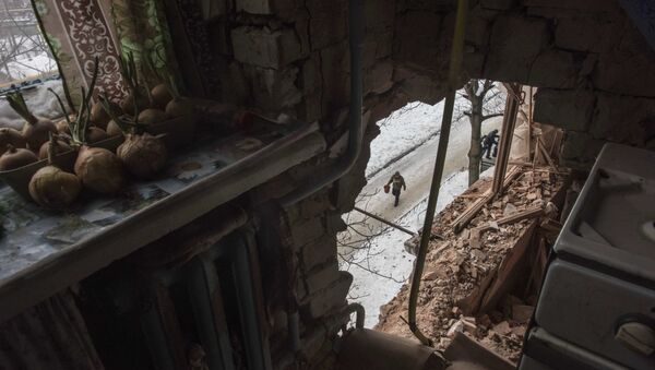 A local resident walking in a street is seen through a hole in an apartment building damaged by shelling in Avdiivka, Ukraine, Saturday, Feb. 4, 2017 - Sputnik Mundo