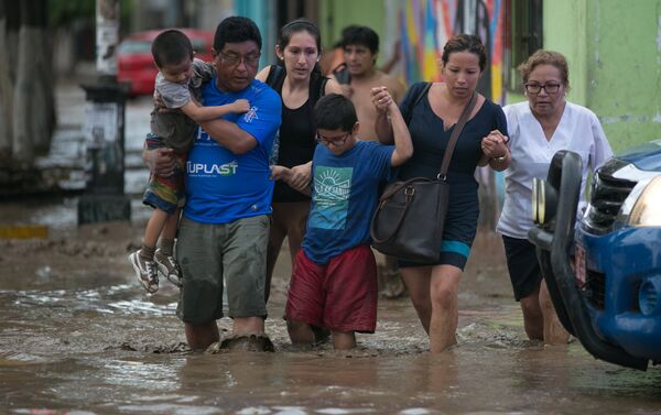 Peruanos cruzan una calle inundada en Trujillo - Sputnik Mundo