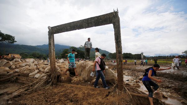 Personas caminan en una zona destruida tras las inundaciones y los deslizamientos de tierra causados por fuertes lluvias en Mocoa, Colombia - Sputnik Mundo
