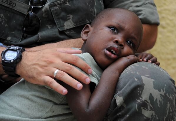 Un soldado de la Misión de las Naciones Unidas para la Estabilización en Haití (Minustah) abraza a un niño que quedó huérfano al morir sus padres en el terremoto de 2010. - Sputnik Mundo