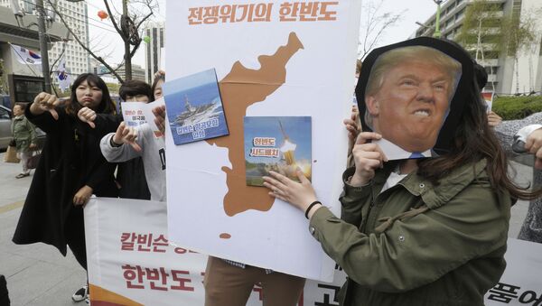 Los manifestantes llevan un recorte del presidente estadounidense Donald Trump y las imágenes del portaviones USS Carl Vinson y del sistema de defensa antimisiles estadounidense THAAD en un mapa de la Península Coreana - Sputnik Mundo
