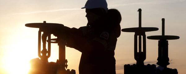Un obrero revisa la válvula de un tubo de petróleo Un obrero revisa la válvula de un tubo de petróleo - Sputnik Mundo