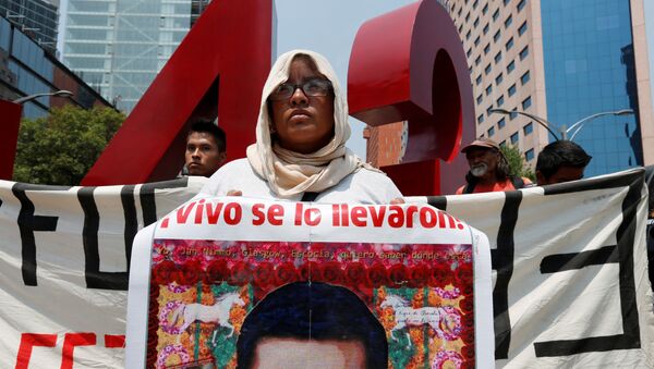Woman holds a poster with an image of one of the 43 missing students of Ayotzinapa - Sputnik Mundo