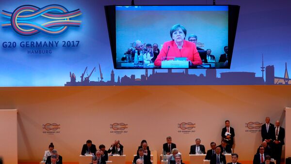 Ángela Merkel, canciller alemana y el logotipo del G20 en Hamburgo - Sputnik Mundo