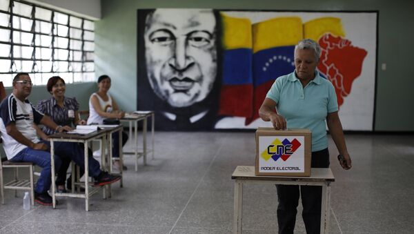 Electoral officials watch as a woman casts her vote at a polling station during the Constituent Assembly election in Caracas, Venezuela - Sputnik Mundo
