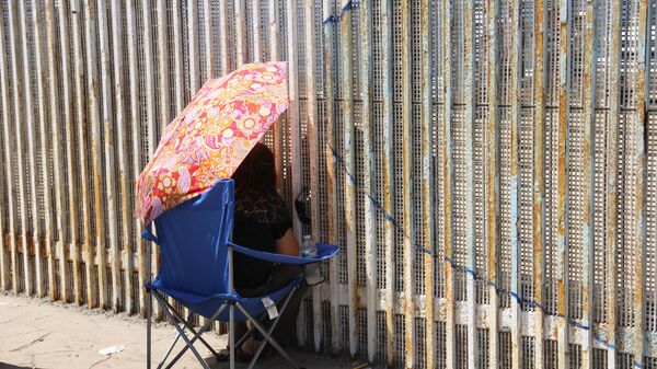 Una mujer habla con sus familiares a través del muro que separa México y EEUU - Sputnik Mundo