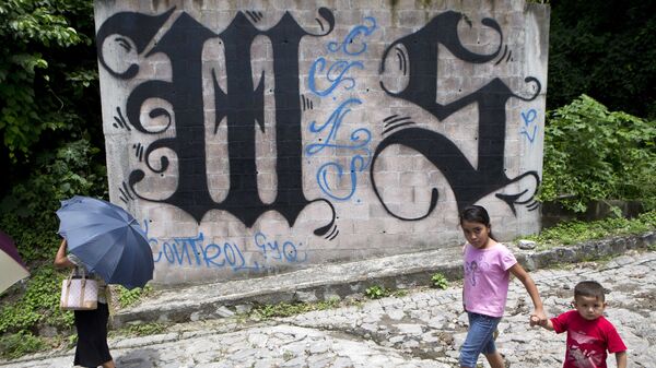 Unos niños pasean al lado de un muro pintado con los símbolos del MS-13 en El Salvador (archivo) - Sputnik Mundo