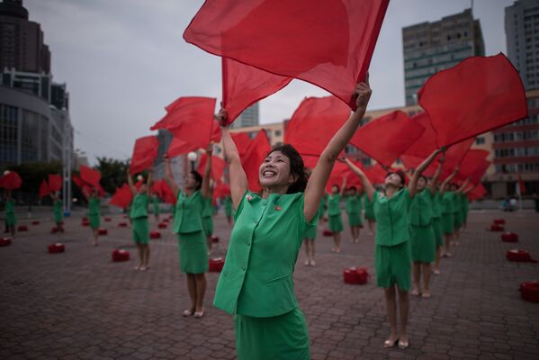 Los miembros de un grupo de propaganda con las banderas de Corea del Norte en las manos, cerca de la estación de ferrocarril de Pyongyang - Sputnik Mundo