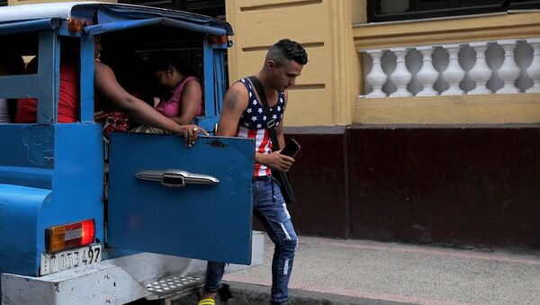 Un hombre, que lleva una camiseta de la bandera de EEUU, se baja de un vehículo en la Habana, Cuba - Sputnik Mundo