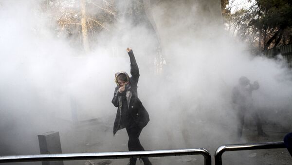 FILE - In this Saturday, Dec. 30, 2017 file photo taken by an individual not employed by the Associated Press and obtained by the AP outside Iran, a university student attends a protest inside Tehran University while a smoke grenade is thrown by anti-riot Iranian police, in Tehran, Iran - Sputnik Mundo