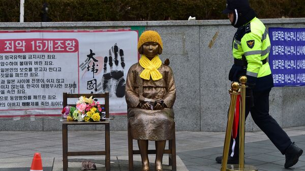 Un policía surcoreano pasa por delante de la estatua de una joven con un vestido tradicional representando a las 'mujeres de consuelo' que sirvieron como esclavas sexuales durante la II Guerra Mundial. - Sputnik Mundo