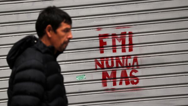 Un hombre camina frente a un grafiti de protesta contra el FMI - Sputnik Mundo