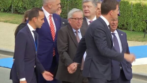 In this Wednesday, July 11, 2018 grab taken from video, European Union leader Jean-Claude Juncker is helped by Netherlands Prime Minister Mark Rutte at Brussels Parc Cinquantenaire, in Brussels, Belgium. - Sputnik Mundo