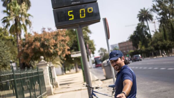 Мужчина фотографируется у электронного табло, которое показывает температуру +50 в Севилье - Sputnik Mundo