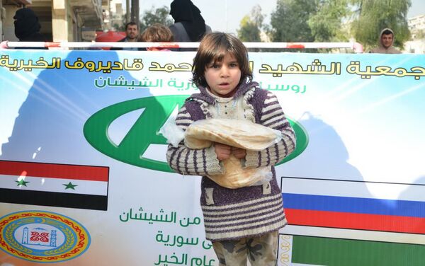 Un niño sirio con el pan que acaba de recibir en el punto de entrega de la ayuda humanitaria - Sputnik Mundo