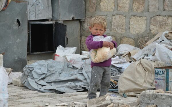 Un niño sirio en Alepo con el pan distribuido por la Fundación Pública Local Ajmat Kadírov - Sputnik Mundo