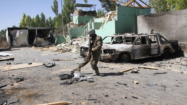 Un miembro de las fuerzas de seguridad afganas junto a vehículos dañados después de una explosión, Afganistán - Sputnik Mundo