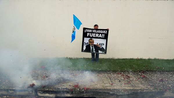 Un manifestante sostiene un cartel frente a la sede de la CICIG en Guatemala - Sputnik Mundo