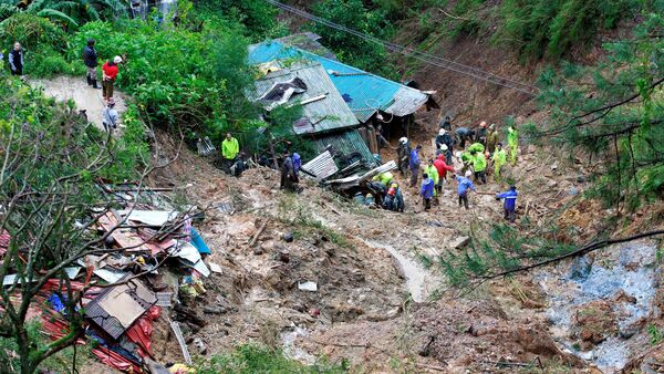 Unos rescatistas buscan a tres ciudadanos enterrados por un deslizamiento durante el tifón Mangkhut - Sputnik Mundo