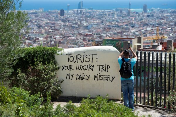 Vista a la ciudad de Barcelona desde el Park Guell, con una inscripción 'Turista: tu viaje de lujo es mi miseria diaria' Vista a la ciudad de Barcelona desde el Park Guell, con una inscripción 'Turista: tu viaje de lujo es mi miseria diaria' - Sputnik Mundo
