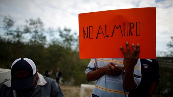 Un inmigrante sostiene una pancarta que dice 'No al muro' - Sputnik Mundo