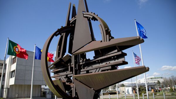 El símbolo de la OTAN y las banderas de Estados que forman parte del bloque militar. - Sputnik Mundo