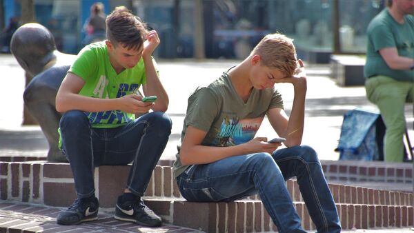 Jóvenes con sus celulares en una plaza - Sputnik Mundo