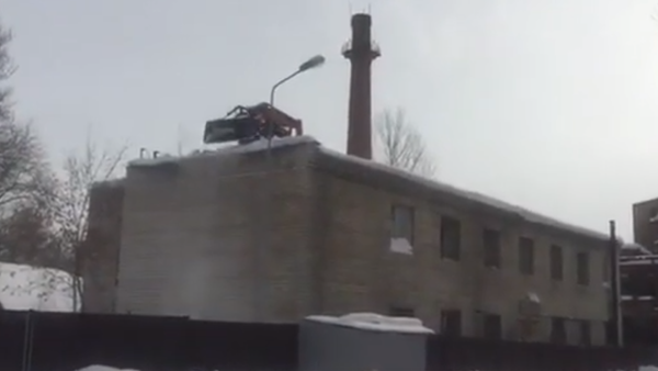 Un tractor quita la nieve del tejado de un edificio - Sputnik Mundo