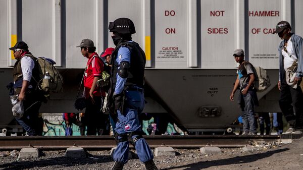 Seguridad privada vigila a migrantes frente a un tren de carga. En la ruta migrante se encontraron al menos cuatro de estas empresas dedicadas a la custodia de las vías, que también ejercen funciones de migración y seguridad pública. - Sputnik Mundo