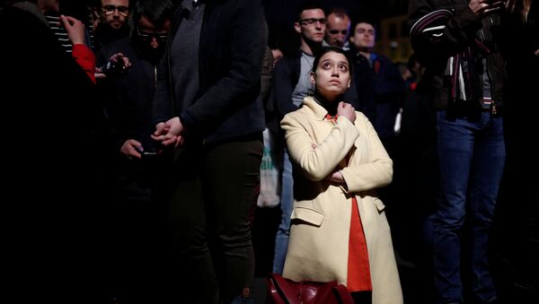 Una mujer se pone de rodillas entre la multitud que observa consternada el incendio de Notre Dame - Sputnik Mundo
